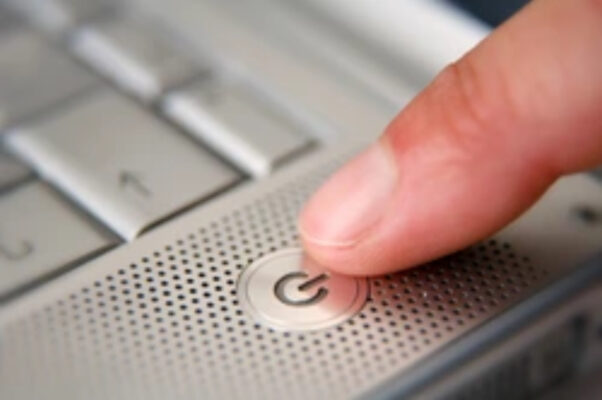 an image of a finger pressing the power button of a laptop